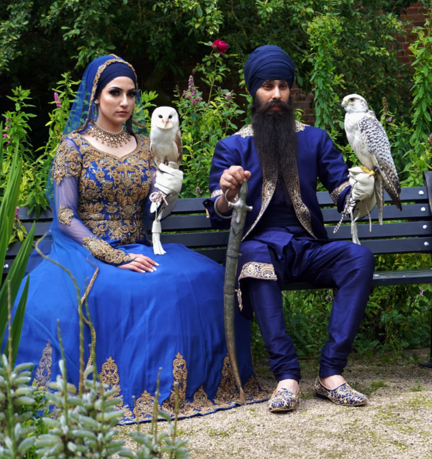 owls-falcon-birds-of-prey-leicestershire-sikh-wedding a sikh bride and groom sitting on a bench holding a barn owl and a Gyrfalcon